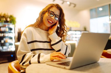 Serbest çalışan kadın, dizüstü bilgisayarda proje için iş arama konusuna odaklanmış, boş zamanlarında internet kurslarının internet sayfalarını karıştıran genç bir kadın ders çalışmaya başlamış. İnternetten alışveriş.