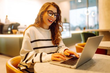 Serbest çalışan kadın, dizüstü bilgisayarda proje için iş arama konusuna odaklanmış, boş zamanlarında internet kurslarının internet sayfalarını karıştıran genç bir kadın ders çalışmaya başlamış. İnternetten alışveriş.