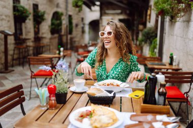 Roma 'nın caddesindeki restoranda İtalyan makarnası yiyen genç bir kadın. İtalyan gastronomisi ve seyahat kavramı. Yiyecek ve içecek..