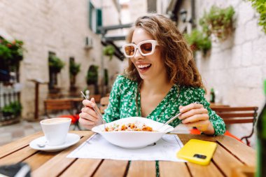 Roma 'nın caddesindeki restoranda İtalyan makarnası yiyen genç bir kadın. İtalyan gastronomisi ve seyahat kavramı. Yiyecek ve içecek..
