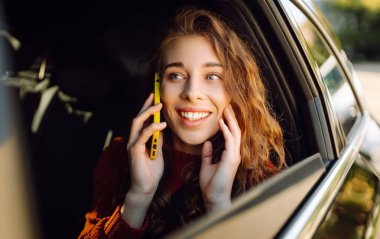 Arabanın arka koltuğunda telefonu olan yolcu kadın. Teknoloji kavramı, internet, blog, arabayla seyahat, iş.