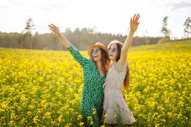 Sarı çiçekli güzel bir tarlada iki genç kadın. Yaz günü çiçek ekerek yürür. Kız arkadaşlar birlikte..