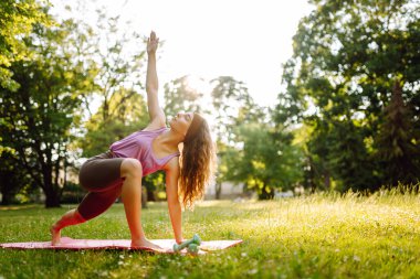 Parktaki kadın spor yapmak için arka planda bir çayıra ve ağaçlara gidiyor. Etkin Yaşam Biçimi.