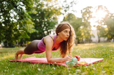 Parktaki kadın spor yapmak için arka planda bir çayıra ve ağaçlara gidiyor. Etkin Yaşam Biçimi.