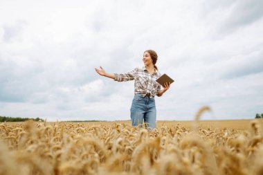 Çiftçi - altın buğday tarlasında ellerinde tabletle bir kadın. Akıllı çiftlik. Tarım, organik bahçe, ekme ya da ekoloji konsepti.