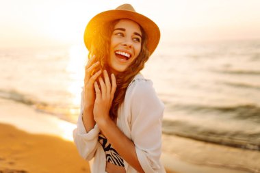 Sahilde yalınayak yürüyen genç bir kadın, gün doğumunda. Seyahat, hafta sonu, rahatlama ve yaşam tarzı konsepti.