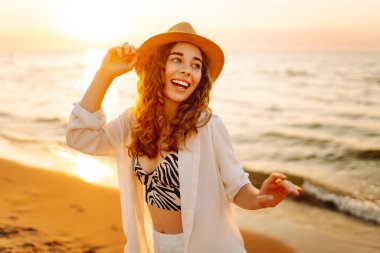 Sahilde yalınayak yürüyen genç bir kadın, gün doğumunda. Seyahat, hafta sonu, rahatlama ve yaşam tarzı konsepti.