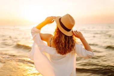 Sahilde yalınayak yürüyen genç bir kadın, gün doğumunda. Seyahat, hafta sonu, rahatlama ve yaşam tarzı konsepti.