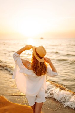 Sahilde yalınayak yürüyen genç bir kadın, gün doğumunda. Seyahat, hafta sonu, rahatlama ve yaşam tarzı konsepti.