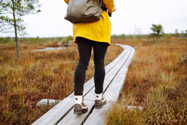 Фото женской ноги, идущей по деревянной дорожке в болотах. Путешествия концепции, изучения. Активный образ жизни.