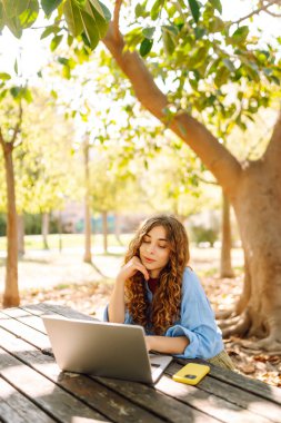 Dizüstü bilgisayarda yazı yazan kız öğrenci üniversite binası, eğitim ve modern teknolojilerin yanında oturuyor..