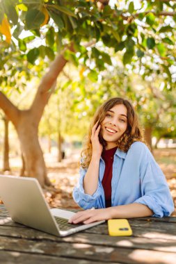 Dizüstü bilgisayarda yazı yazan kız öğrenci üniversite binası, eğitim ve modern teknolojilerin yanında oturuyor..