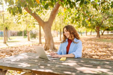 Dizüstü bilgisayarda yazı yazan kız öğrenci üniversite binası, eğitim ve modern teknolojilerin yanında oturuyor..