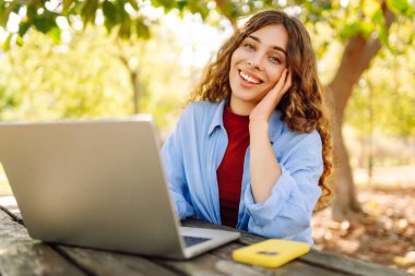 Dizüstü bilgisayarda yazı yazan kız öğrenci üniversite binası, eğitim ve modern teknolojilerin yanında oturuyor..