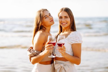 Kumsalda şarapla mutlu iki kadın. Yaz tatilindeki kadın turistler. Kızlar partisi..