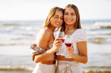 Kumsalda şarapla mutlu iki kadın. Yaz tatilindeki kadın turistler. Kızlar partisi..