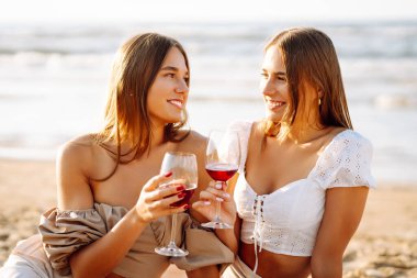 Kumsalda şarapla mutlu iki kadın. Yaz tatilindeki kadın turistler. Kızlar partisi..