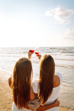 Kumsalda şarapla mutlu iki kadın. Yaz tatilindeki kadın turistler. Kızlar partisi..