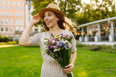 Bir buket kır çiçeği tutan mutlu kadın. Özgürlük ve mutluluk. Yaz zamanı.