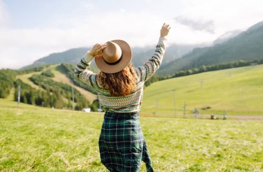 Yeşil çimen tarlasında yürüyen sevimli bir kadın manzaraya hayran. Doğanın tadını çıkarıyorum. Macera ve seyahat. 