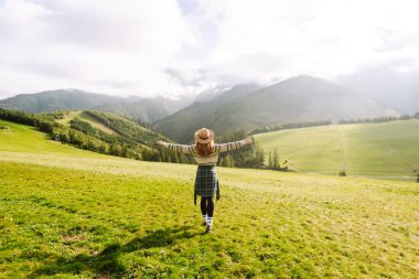 Yeşil çimen tarlasında yürüyen sevimli bir kadın manzaraya hayran. Doğanın tadını çıkarıyorum. Macera ve seyahat. 