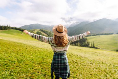 Yeşil çimen tarlasında yürüyen sevimli bir kadın manzaraya hayran. Doğanın tadını çıkarıyorum. Macera ve seyahat. 