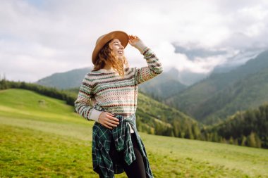 Yeşil çimen tarlasında yürüyen sevimli bir kadın manzaraya hayran. Doğanın tadını çıkarıyorum. Macera ve seyahat. 