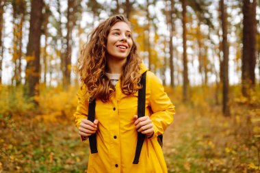 Sırt çantası taşıyan aktif genç bir kadın güzel bir sonbahar gününün tadını çıkarıyor. Sonbahar manzarası. Sakinlik ve sükunet. Seyahat, turizm konsepti.