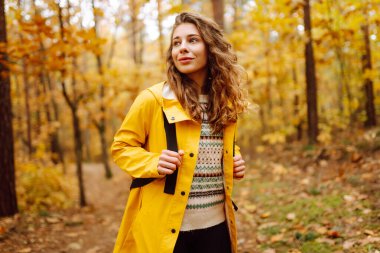 Sırt çantası taşıyan aktif genç bir kadın güzel bir sonbahar gününün tadını çıkarıyor. Sonbahar manzarası. Sakinlik ve sükunet. Seyahat, turizm konsepti.