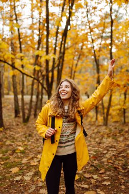Sırt çantası taşıyan aktif genç bir kadın güzel bir sonbahar gününün tadını çıkarıyor. Sonbahar manzarası. Sakinlik ve sükunet. Seyahat, turizm konsepti.