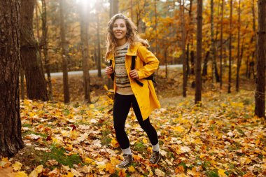 Sırt çantası taşıyan aktif genç bir kadın güzel bir sonbahar gününün tadını çıkarıyor. Sonbahar manzarası. Sakinlik ve sükunet. Seyahat, turizm konsepti.