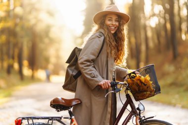 Altın sonbahar parkında bisiklet süren genç ve güzel bir kadın. Açık hava portresi. Etkin yaşam biçimi.