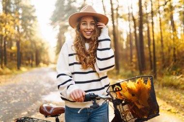 Altın sonbahar parkında bisiklet süren genç ve güzel bir kadın. Açık hava portresi. Etkin yaşam biçimi.