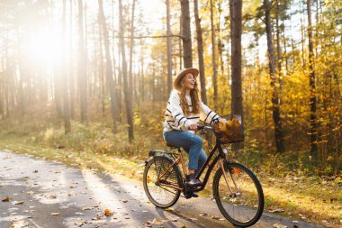 Altın sonbahar parkında bisiklet süren genç ve güzel bir kadın. Açık hava portresi. Etkin yaşam biçimi.
