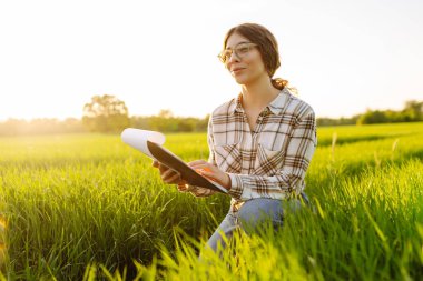 Kadın çiftçi araştırmacı, veriyi artırmanın yollarını analiz etmek için tarladaki yeşil filizli bitkileri toplamak için bir defter kullanıyor. Tarım teknolojisi