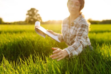 Kadın çiftçi araştırmacı, veriyi artırmanın yollarını analiz etmek için tarladaki yeşil filizli bitkileri toplamak için bir defter kullanıyor. Tarım teknolojisi