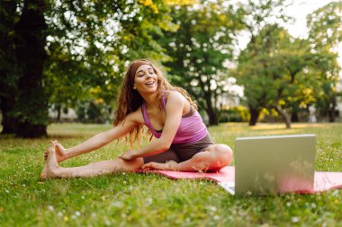 İnternette pilates dersi veren mutlu bir kadın. Dizüstü bilgisayarda spor rehberliği ya da çevrimiçi eğitim ya da antrenör talimatları yapıyorum. Çevrimiçi eğitim..