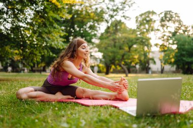 İnternette pilates dersi veren mutlu bir kadın. Dizüstü bilgisayarda spor rehberliği ya da çevrimiçi eğitim ya da antrenör talimatları yapıyorum. Çevrimiçi eğitim..