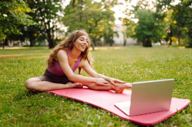 İnternette pilates dersi veren mutlu bir kadın. Dizüstü bilgisayarda spor rehberliği ya da çevrimiçi eğitim ya da antrenör talimatları yapıyorum. Çevrimiçi eğitim..