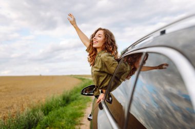 Doğanın tadını çıkaran güzel bir kadın, araba sürerken pencereden dışarı bakıyor. Yaşam tarzı, seyahat, turizm, doğa, aktif yaşam.