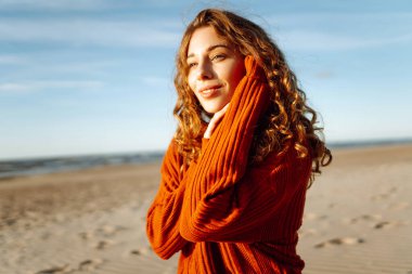 Soğuk havada sahilde güzel bir kadının portresi. Sonbahar havası. Seyahat, doğa, hafta sonu, rahatlama ve yaşam tarzı konsepti.