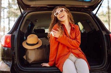 Mutlu kadın doğanın tadını çıkarırken arabasının bagajında tek başına oturuyor. Yaz tatili seyahatleri..