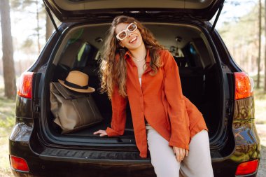 Mutlu kadın doğanın tadını çıkarırken arabasının bagajında tek başına oturuyor. Yaz tatili seyahatleri..