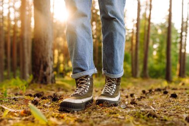 Ormanda yürümek için bot giyen bir yetişkinin ayakları. Doğada yürüyen ayaklar. Boş zamanlardaki sağlıklı yaşam tarzı.