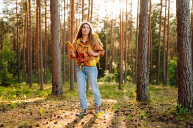 Sonbahar ormanlarında seyrüsefer için mobil uygulama kullanan genç bir kadın. En iyi yolu bulmaya çalışan mutlu bir turist. Aktif yaşam tarzı, seyahat kavramı