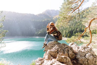 Sırt çantalı kadın gezgin güzel gölün, dağların ve yeşil ormanın tadını çıkarıyor. Çevre turizmi. Etkin yaşam biçimi.