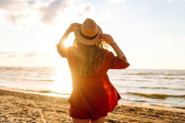 Gün batımında sahilde yaz gününün tadını çıkaran güzel bir kadın. Beyaz kadın tatilde çok iyi vakit geçiriyor. Yaşam tarzı, turizm, doğa, aktif yaşam.