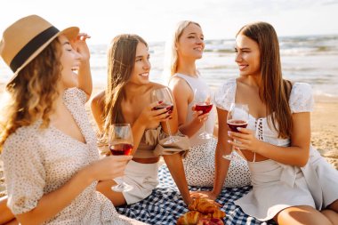 Plaj pikniğinde şarap kadehli mutlu kadınlar. Kutlama, arkadaşlar, bekarlığa veda partisi ve tatil konsepti. Kızlar partisi..