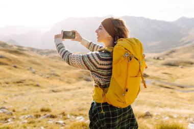 Genç bir kadın, altın saat boyunca dağlık bir arazide yürüyüş yaparken bir anı yakalar.