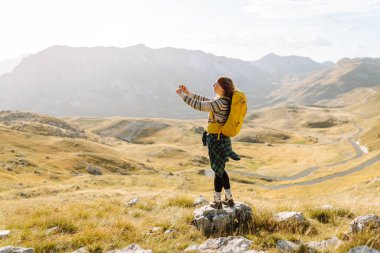 Genç bir kadın, altın saat boyunca dağlık bir arazide yürüyüş yaparken bir anı yakalar.